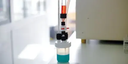 BOLA Mikro-Reaktionsgefäß aus PFA/PTFE mit Ventilen, blauem Medium und roter Testflüssigkeit im Labor.